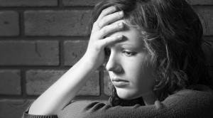 Teenage girl siiting against brick wall in a depressed state