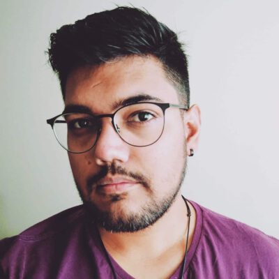 Thiago Augusto, olhando para a frente, usando óculos, e camiseta roxa