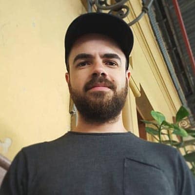 Selfie de Édipo Barreto. Homem branco, com barba castanha. Está usando boné e vestindo uma camiseta cinza.